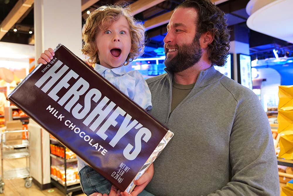 Dad and child holding World's Largest HERSHEY'S Bar